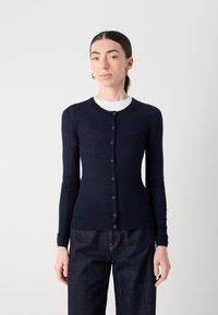 Marinblå ribbad cardigan gjord av mjukt tyg, med rund halsringning, lång ärm och matchande knappar framtill.