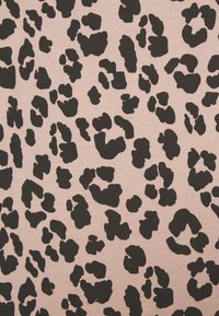 Látka s leopardím vzorem na jemně růžovém pozadí, s výraznými černými skvrnami různých tvarů a velikostí, měkká textura a střední pružnost.