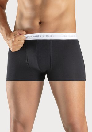 Black cotton boxer briefs with a white elastic waistband featuring "COPENHAGEN STUDIOS" in gray text. Soft texture, fitted design.