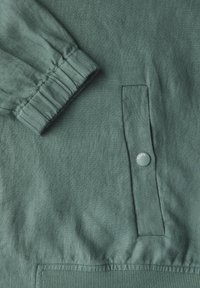 Groene linnen jas met details zoals een gathered mouwopening, een klepzak met een drukknoop en een ribgebreide tailleband.