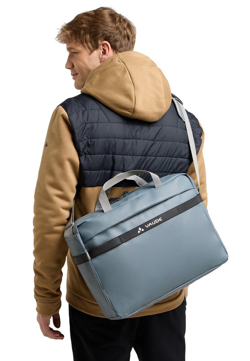 Grau Schultertasche mit einem eleganten Design, aus glattem Material gefertigt, mit einem schwarzen Akzentband und VAUDE-Branding, getragen an einem grauen Schultergurt.