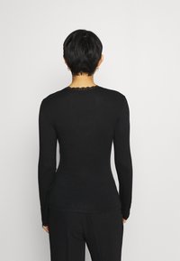 Svart långärmad topp med en figurnära passform, försedda med en spetsbesättning vid halsringningen och en mjuk tygstruktur. Inga synliga mönster eller detaljer.