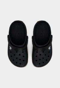 Ζεύγος μαύρων Crocs clogs με λουριά στη φτέρνα, οπές αερισμού στο πάνω μέρος και λογότυπο στο πλάι, εμφανιζόμενα από πάνω σε λευκό φόντο.