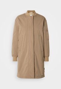 Μπλε μακρύ παλτό με ψηλό γιακά, φερμουάρ στο μπροστινό μέρος και ελαστικά μανίκια. Διαθέτει δύο πλαϊνές τσέπες και μία τσέπη με φερμουάρ στο αριστερό μανίκι.