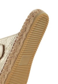 Gouden metallic sandaal met een geweven juteaccent en een textuur rubberen zool. De rand heeft een gevlochte afwerking en verticale ribbels op de zool.