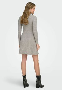 Robe en tricot côtelé gris avec manches longues, silhouette ajustée, jupe évasée et col rond, associée à des bottines noires à la cheville.