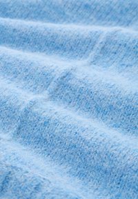 Jasnoniebieska tkanina o teksturowanej, miękkiej i puszystej powierzchni, z subtelnym wzorem tkanym i delikatnymi falami. Idealna na przytulne ubrania lub dodatki.