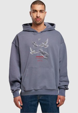Grå hoodie med en frontlomme. Har et grafik med duer og kæder, med ordet "FREEDOM" i rødt. Blødt materiale og løs pasform.