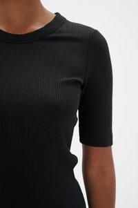 Melns ribots īsās piedurknes tops ar apaļu izgriezumu. Audums izskatās elastīgs, tam ir gluda tekstūra un viegla vertikāla raksts.