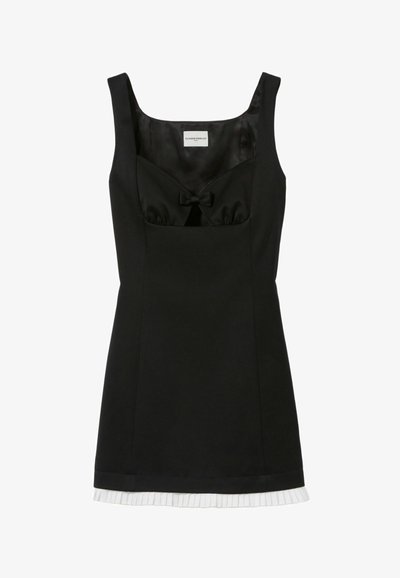 Vestido negro sin mangas con un corpiño ajustado, detalle de lazo en el escote y un dobladillo blanco plisado, hecho de una tela suave.