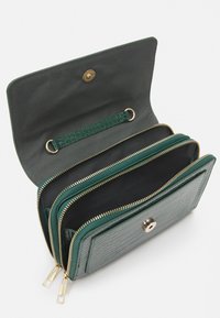 Portafoglio verde in ecopelle con texture a coccodrillo, zip dorate e chiusura a scatto. L'interno presenta diversi scomparti e una fascia.
