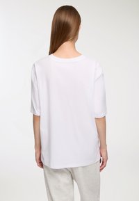 T-shirt in cotone bianco con maniche corte e collo rotondo. Il retro è semplice, presenta una vestibilità rilassata e morbida.