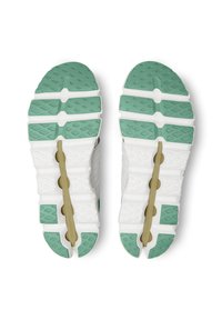 Baskets de course avec une tige blanche et des semelles extérieures en caoutchouc vert. Elles présentent un motif de traction texturé et un design léger pour une meilleure adhérence.