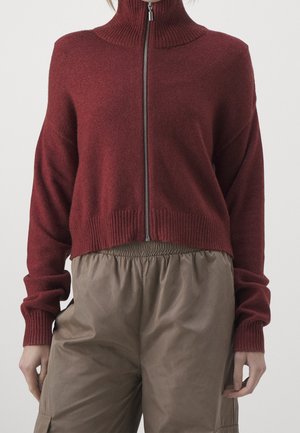 Bordeaux ritsweater met hoge ribbelkraag, cropped fit en lange mouwen, gecombineerd met broeken met elastische tailleband in bruin.