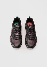 Tenis de rede pretos e roxos com um design texturizado, apresentando atacadores pretos e um interior com gradiente verde e rosa. Sola de borracha.