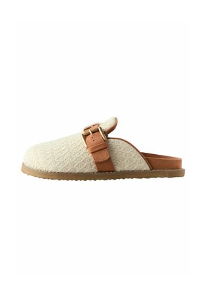 Textured cream slip-on sandal with brown leather strap and buckle, featuring a patterned upper and rubber sole for grip.