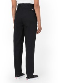 Svarta byxor med hög midja, rak benform och bakfickor. Tyget verkar rejält och har en logotyp ovanför den högra fickan.