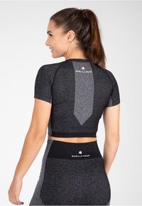 Juodas sportinis trumpas topas su trumpomis rankovėmis, turintis tekstūruotą raštą ir pilkas akcentus, pažymėtas "GORILLA WEAR" ant nugaros.