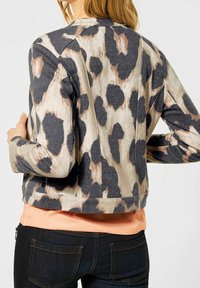 Leopardmönstrad jacka i mjukt tyg, med en kort design, rund halsringning och lång ärmar med kontrasterande grå och beige mönster.