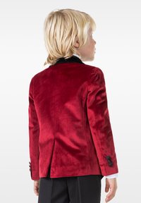 Chaqueta de terciopelo rojo con un cuello de terciopelo negro, que presenta una única abertura y botones negros en las mangas. Diseño clásico ajustado.