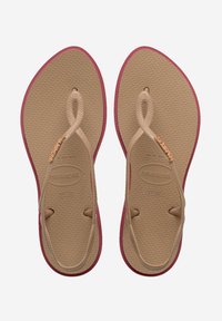 Flip-flop sandaler med en tan gummisål og bordeauxfarvede accenter. Tekstureret fodseng og flettede stropper med en dekorativ metaldetalje.