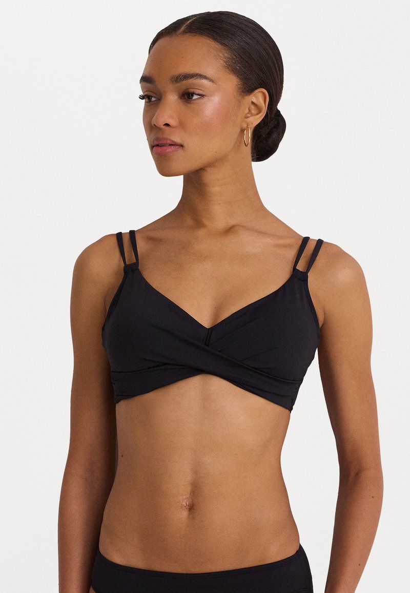 Svart bikini-top med kryssdesign foran, tynne justerbare stropper og en glatt tekstur. Minimalistisk stil med en ren silhuett.