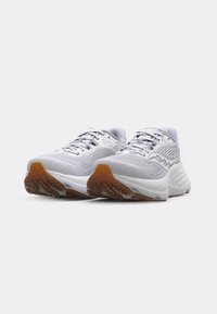 Chaussures de sport blanches avec un dessus en mesh texturé, des accents réfléchissants, une semelle intermédiaire épaisse et une semelle extérieure en caoutchouc durable dotée d'un motif antidérapant.
