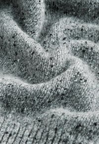 Tissu en tricot gris texturé avec des touches de noir et de bleu, présentant une qualité douce et duveteuse ainsi qu'un motif de surface ondulée.
