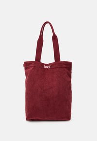 Borsa tote in corda rossa con manici lunghi e logo Levi's bianco ricamato vicino al centro superiore su uno sfondo chiaro e uniforme.