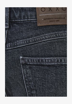 Jeans in denim scuro con un tessuto testurizzato. Presentano un'etichetta in pelle e cuciture a contrasto. Include un design con tasche posteriori.