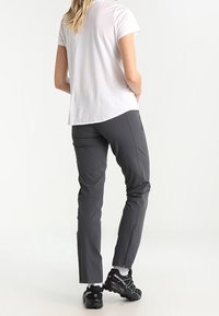 Grijze outdoorbroek met een slanke pasvorm, gemaakt van lichtgewicht stof. Gecombineerd met een wit T-shirt en zwarte wandelschoenen met gekleurde accenten.