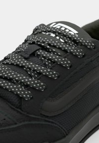 Zwarte sneaker met een gestructureerde synthetische bovenkant, donkergrijze rubberen zool, gestreepte veters met witte accenten en een logo op de tong.