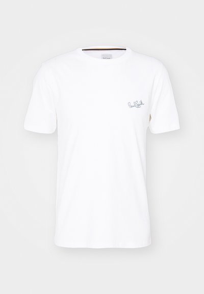 Valge puuvillane T-särk lühikeste varrukatega, ümar kaelus ja diskreetne sinine tikand vasakul rinnal. Sile tekstuur.