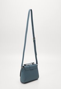 Bolso de mano de cuero verde azulado con un diseño estructurado, que presenta un asa superior, correa de hombro ajustable y acentos de hardware en tono dorado.