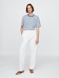 Striped t-skjorte i blått og hvitt, med rund hals og korte ermer. Høyt liv hvite bukser med avslappet passform og cropped lengde.
