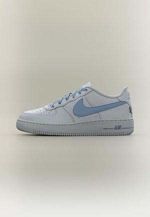 Baskets basses blanches Nike Air Force 1 avec virgule, lacets et marquage "AIR" sur la semelle intermédiaire en bleu clair, sur fond neutre.