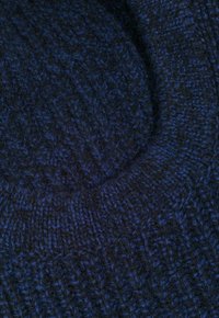 Dziana czapka w ciemnym granatowym kolorze o różnych teksturach i wzorach, z przylegającym prążkowanym wykończeniem. Miękki, gruby materiał z wełny.