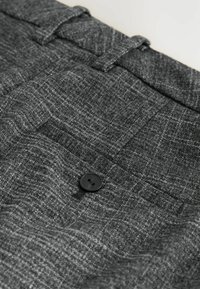Dettaglio dei pantaloni in tessuto grigio texturizzato con tasca posteriore dotata di un bottone nero e passante per cintura sulla vita.
