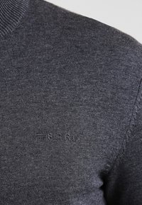 Tummanharmaa neulottu neulepaita, jossa on resorikaulus; edessä hienovarainen kohokuvioitu "ESPRIT"-logo, joka korostaa sileää pintaa.