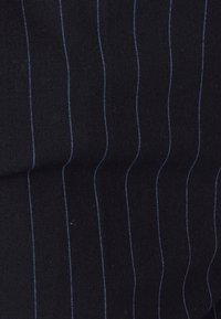 Donker, gestructureerd stof met verticale blauwe streepjes. Het materiaal lijkt iets harig, met contrasterende donkere en lichte draadlijnen.