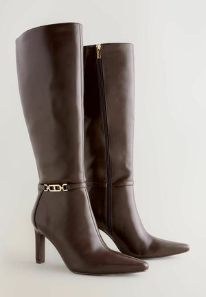 Brūni ceļgala augstuma zābaki ar papēdi, izgatavoti no gludas ādas, ar sānu rāvējslēdzēju, norakstītu purngalu un zelta toņu sprādzi ap potīti.