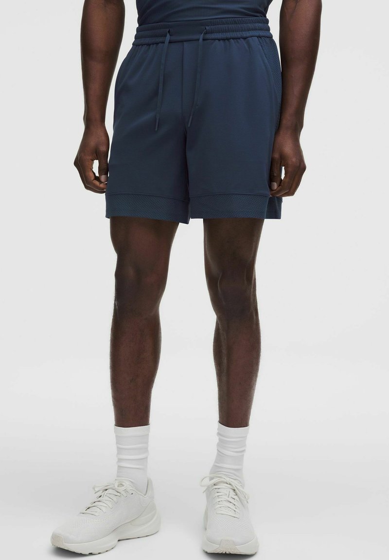 Granatowe szorty sportowe, wykonane z lekkiego materiału, posiadają elastyczny pas, sznurek oraz teksturowane akcenty z siateczki u dołu.