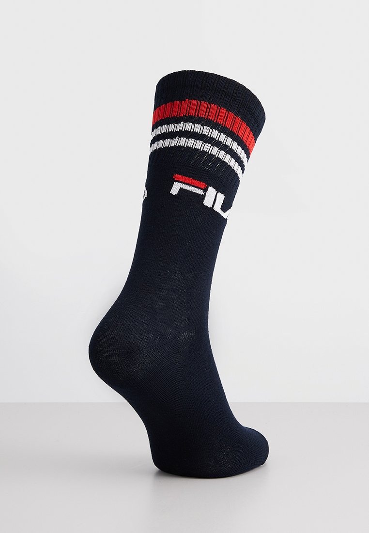 Granatowa skarpetka z prążkowanym ściągaczem, z czerwonymi, białymi i czarnymi paskami oraz logo "FILA" wyszytym na biało. Miękki, elastyczny materiał.