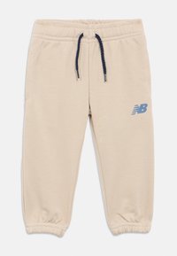 Pantaloni sportivi beige per bambini con elastico in vita, cordino blu navy, polsini elasticizzati e logo blu New Balance sulla gamba destra.