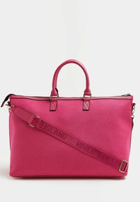 Sac fourre-tout en tissu rose avec deux poignées, bandoulière amovible présentant un texte en relief. Fermeture éclair en haut, design structuré.
