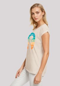 Beige cotton t-shirt with a round neckline and short rolled sleeves. Front features a colorful striped graphic in blue, green, orange.