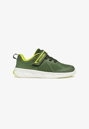 Scarpa da ginnastica per bambini verde e gialla con parte superiore in maglia, cinturino in Velcro, lacci elastici, suola bianca e tirante sul tallone, vista laterale.