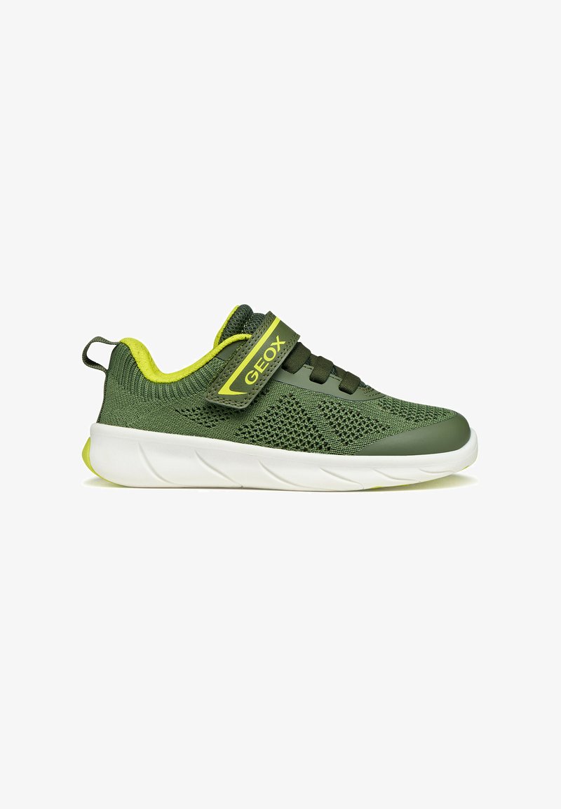 Scarpa da ginnastica per bambini verde e gialla con parte superiore in maglia, cinturino in Velcro, lacci elastici, suola bianca e tirante sul tallone, vista laterale.