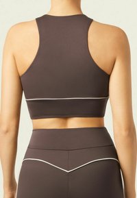 Brown athletic crop top with a high neckline and racerback design. Features white piping details along the bottom hem. Smooth texture.