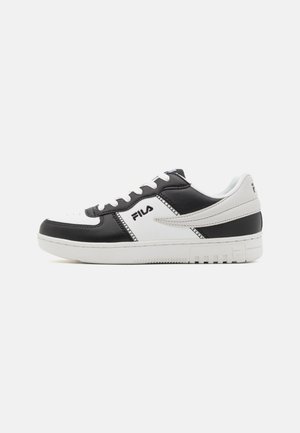 Black and white leather sneakers with perforated toe, contrasting textures, and Fila branding. Features flat laces and a rubber sole.